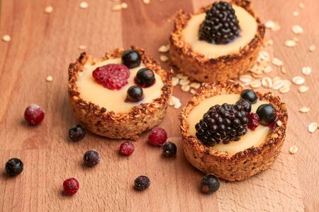 Healthy cereals muffins with berries and yellow cream on the wooden deskの写真素材