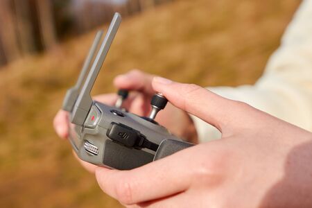 Close up womans hands holding a remote controller of drone. Shooting video in the air. Quadrocopter flight conceptの写真素材