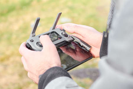 Close up mans hands holding drone remote controller with smartphone in the field. Concept of aerial shooting and flying, San Francisco, May 2020.のeditorial素材
