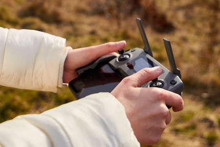 Close up womans hands holding a remote controller with a smartphone. Concept of aerial footage, San...