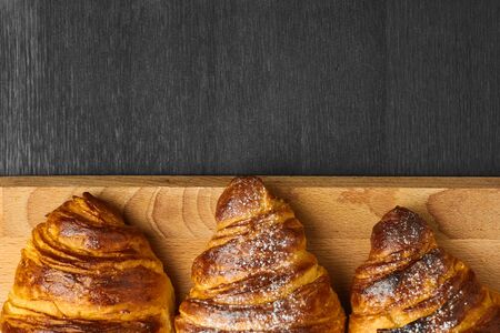 Top view of three croissants on a dark background with copy space. Homemade baking from puff doughの写真素材