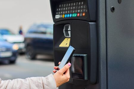 Woman using her mobile phone for payment for public parking by NFC. Contactless payment system with copy space.の写真素材