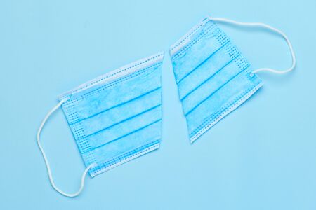 Two parts of cut surgical mask on a blue background with copy space. Finish of coronavirus pandemic....