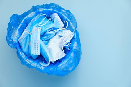 Mask thrown in the trash. Discarded surgical masks. Medical waste with copy space on a blue background. Over of coronavirus, SARS-CoV-2 pandemic.の写真素材