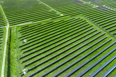 Top view on solar panels in the field with green grass. Big modern solar station producing renewable...