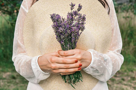 Female holding a hat and bouquet of lavender in her hand. Provence rural styeの写真素材