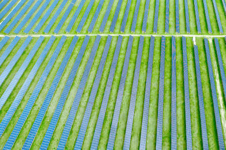 Top view of solar power station for production of electricity. Vertical straight lines of solar panels in the green field. Renewable eco friendly energy source.の写真素材