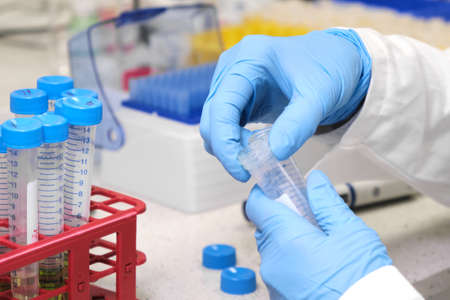 Sample preparation process by analytical chemist. Close up womans hand taking falcone tube and...