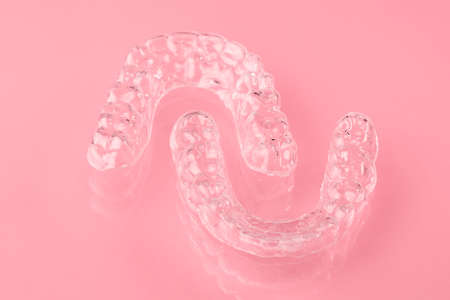 Invisible aligner or retainer for the upper and lower teeth on the pink background. Orthodontic...
