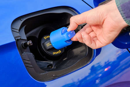 Close up mans hand opening a tank for Ad Blue fluid of a blue car. Diesel exhaust fluid or DEF for reduction of air pollution, October 2020, Prague, Czech Republicのeditorial素材