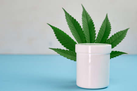 Leaf of cannabis and plastic package or jar with copy space with cream contained hemp oilの写真素材
