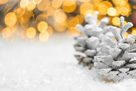 Pine cones on the snow with Christmas decoration on the background with copy space.の写真素材