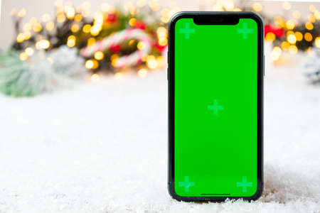 Mobile phone with chromo key on the screen with copy space on the Christmas decoration backgroundの写真素材