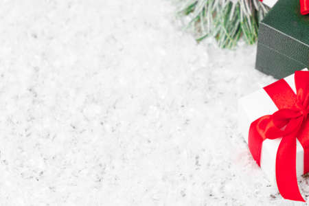 New year white and green gifts with red ribbon on the snow with copy space. Christmas composition