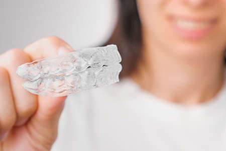 Close up of clear aligners in hand of woman. Orthodontic treatment for whitening and straightening teeth.の写真素材