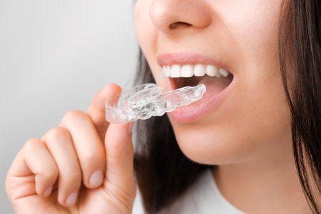 Close up of a young woman adjusting transparent aligners. Taking care of teeth. Orthodontic...