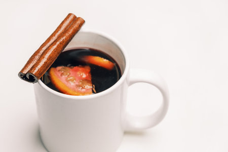 Mug with mulled hot wine with orange and cinnamon stick on the white background.の写真素材