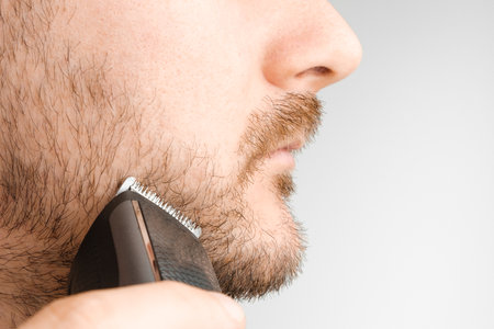 Front view on the man shaving his cheek using electric razorの写真素材