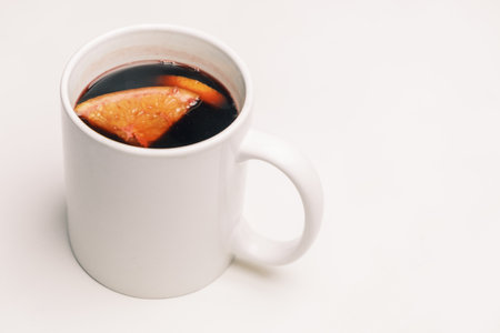 Mug with mulled hot wine with orange on the white background.の写真素材