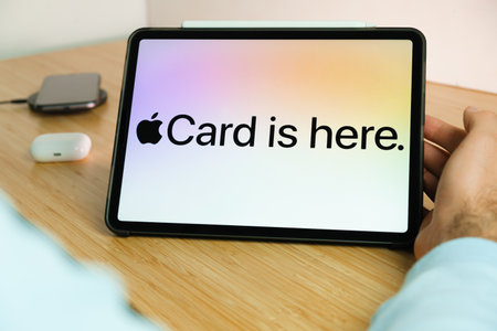 Apple Card logo on the screen of iPad tablet with smart phone iPhone charging on the wireless...