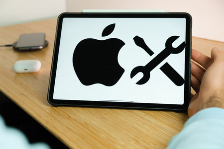 Apple repair logo on the screen of iPad tablet with smart phone iPhone charging on the wireless...