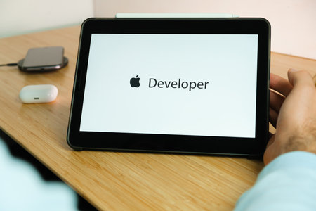 Apple developer logo on the screen of iPad tablet with smart phone iPhone charging on the wireless charger and airpods in the case on the background, November 2020, San Francisco, USAのeditorial素材