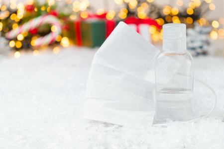 Face mask and sanitizer on the snow on the Christmas background. New year gift concept.の写真素材