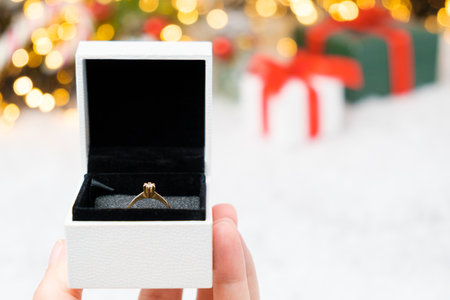 A box with gold ring on the snow with Christmas background. Marriage proposal at New Year Eve. Copy spaceの写真素材
