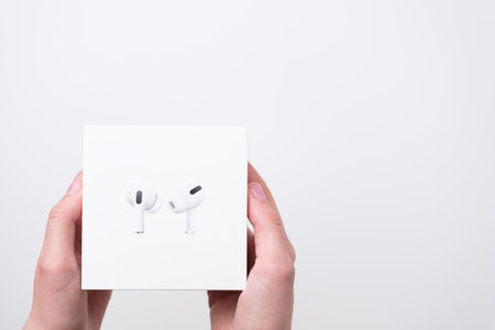 AirPods box in woman hands on the grey background with copy space, December 2020, San Francisco, USA