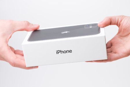 Man and woman hand holding a box with black iPhone 11 on the grey background, December 2020, San Francisco, USAのeditorial素材