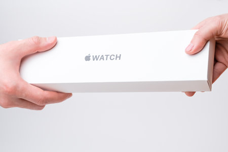 Man and woman hand holding a box with Apple watch on the grey background, December 2020, San...