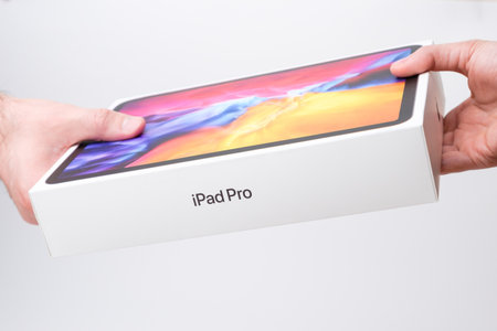 Man and woman hand holding a box with IPad Pro on the grey background, December 2020, San Francisco,...