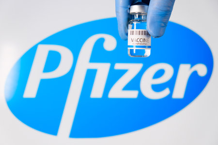Pfizer vaccine in the bottle in doctors hand in rubber gloves on the background of logo, January 2021, San Francisco, USAのeditorial素材