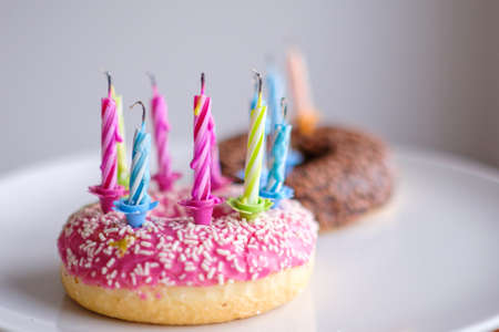 Colorful donuts with pink and chocolate icing with candles for birthday party.