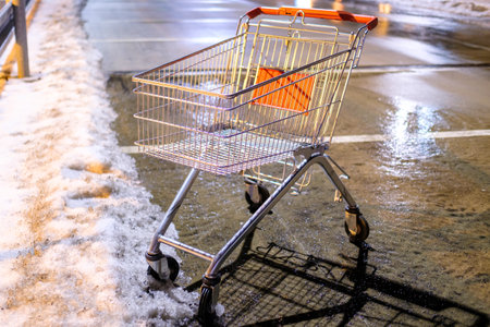An abandoned shopping cart standing on the street near supermarket in the winter.の写真素材