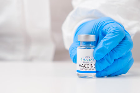 Bharat biotech vaccine against SARS-Cov-2, coronavirus or Covid-19 put on the table by medical worker in the rubber gloves.のeditorial素材