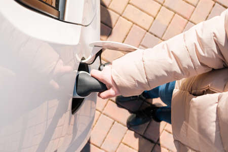 Top view of woman hand inserting the power cable supply plugged into the electric car for rechargingの写真素材