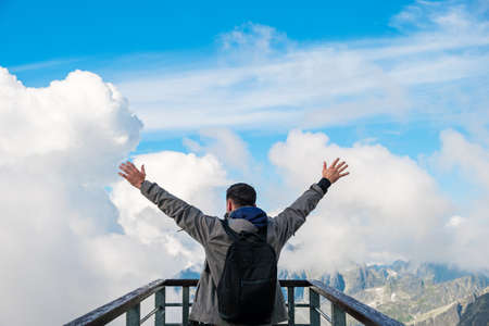 Tourist standing on the observation deck and enjoying of amazing view of mountains peak and cloudsの写真素材