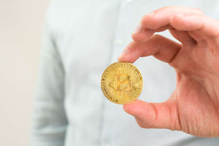 Close up Gold bitcoin coin in mans hand.の写真素材