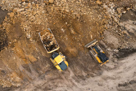 Heavy industrial excavator digs the ground and transfers it to the truck.の写真素材