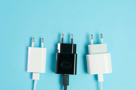 Power plugs with USB A and USB type C connectors from smartphone charger on the blue background with...
