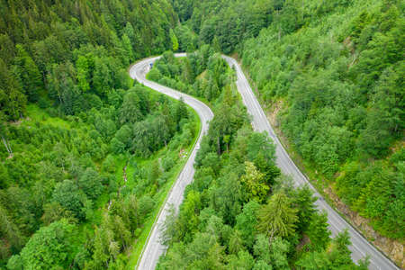 Aerial view of mountain road in the forest with moving cars