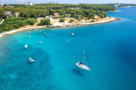 Aerial view of sailboat and small boats or yachts in the turquoise waters of the Adriatic sea close...