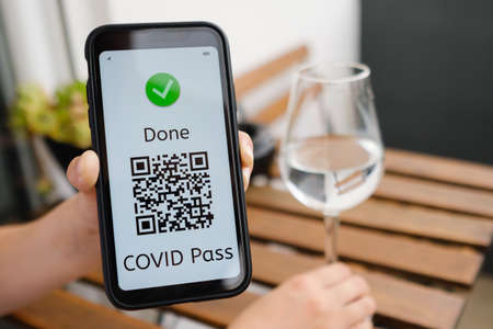 Woman demonstrates Covid pass application or digital health passport with QR code in mobile phone...
