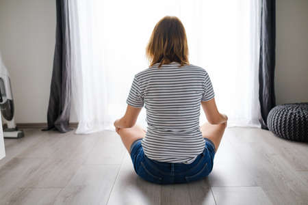 Young woman meditates or practicing yoga in the living room