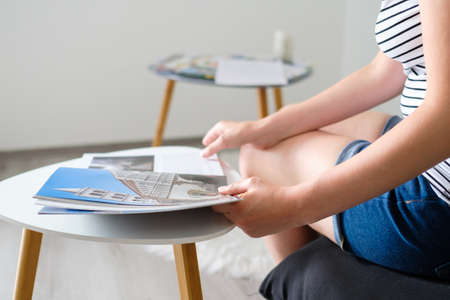 Young woman reading a catalog or travel magazine and chooses a destination to the trip in a...