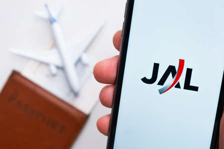 JAL airline company app or logo displayed on a mobile phone with passport, boarding pass and plane on the background, September 2021, San Francisco, USAのeditorial素材