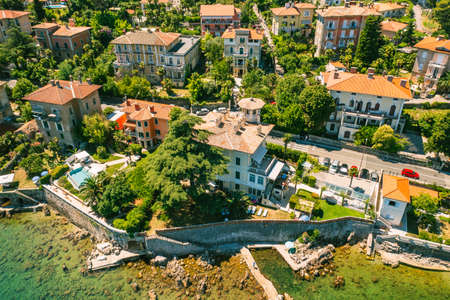 Beautiful villas near the coast of rocky beach in a small town Lovran, Croatia. Arial view of Lungomare sea walkway with transparent water.の写真素材