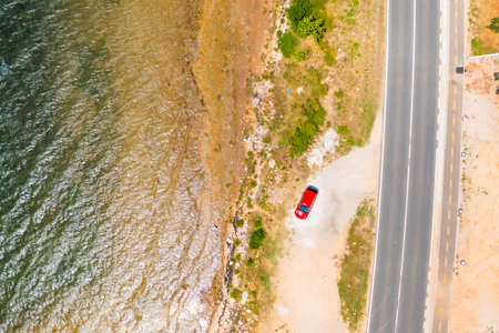 Top view on the red car parking near the beach of Adriatic sea and field with fruit trees.の写真素材