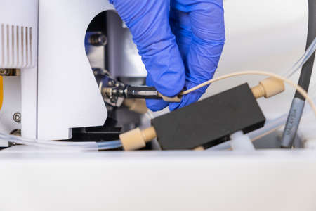 Chemist connecting nebulizer to ion source of mass spectrometer. Liquid chromatography with mass...
